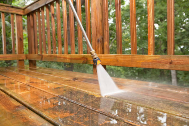Uing a pressure washer to clean a wooden deck.